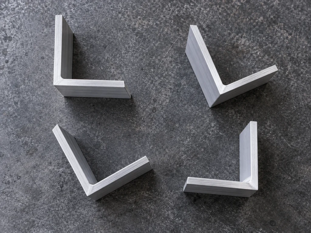 Four aluminum angle sections seen from above on a gray bench