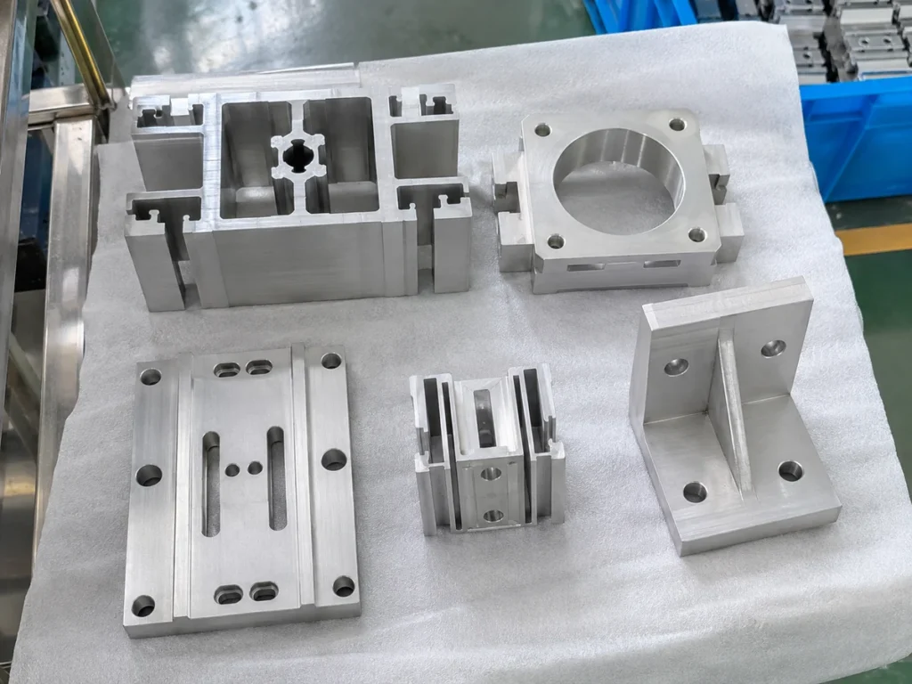 Aluminum profiles, a flange and brackets arranged separately on a white protective foam sheet.