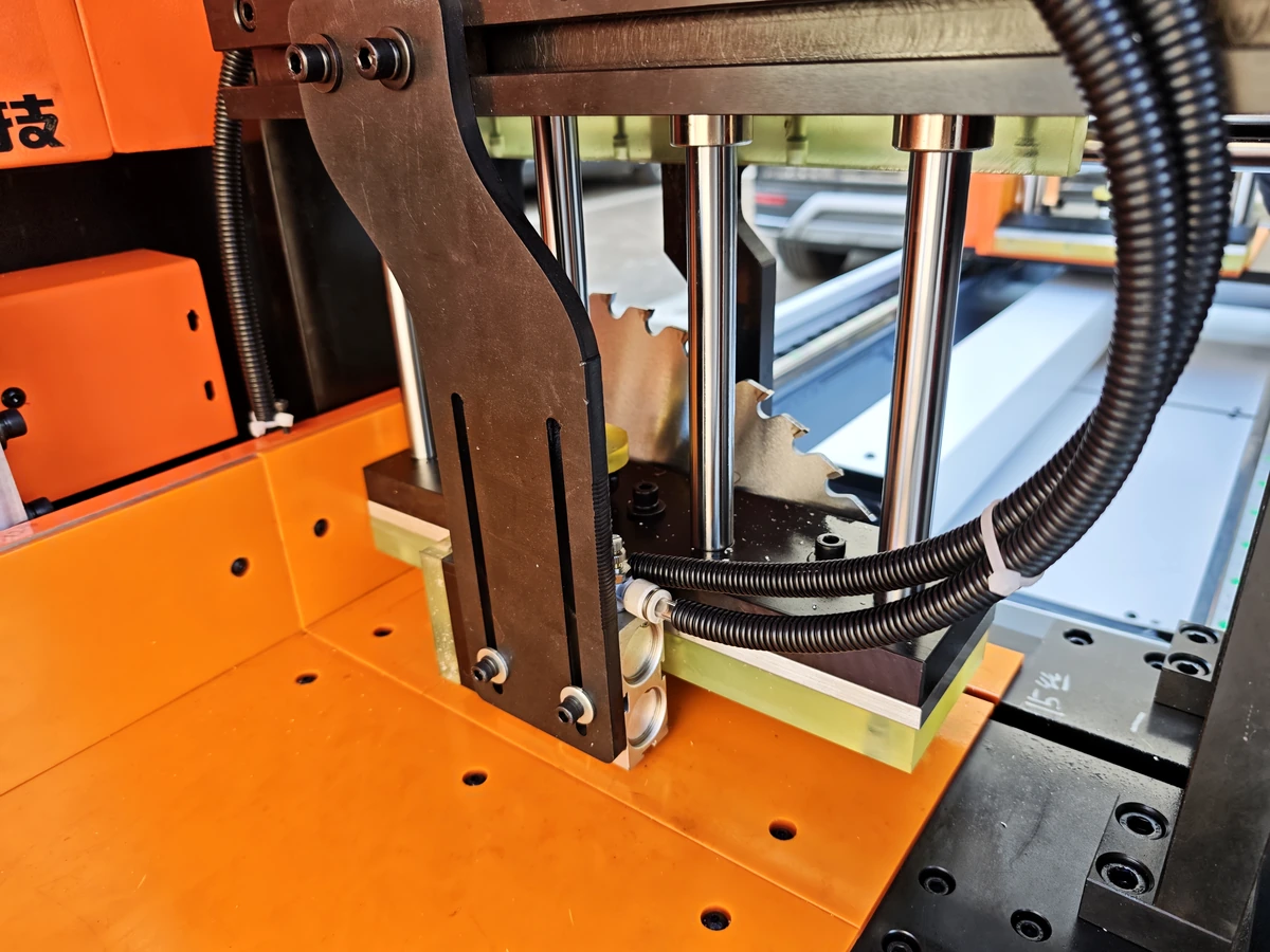Circular saw blade partly visible beside hold-down components in a machine detail view